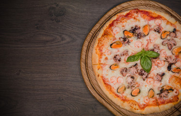 Hot piece of pizza with melted cheese on a rustic wooden table