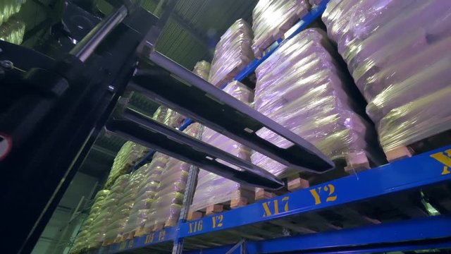 A stackers forks moving from a shelved cargo pallet.