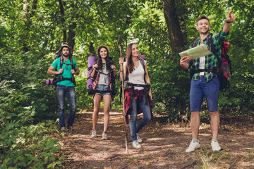 Trekking, camping and wild life concept. Four best friends are hiking in the spring woods, the guy...