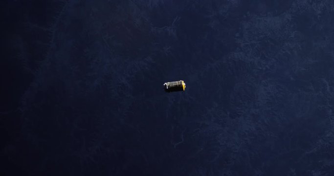 Small satellite flies over Earth, outer space