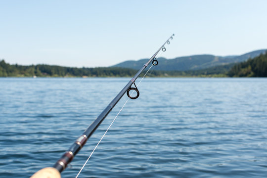 Fishing rod on a lake with mountains in the background.