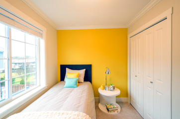 Modern yellow bedroom interior with blue and yellow pillows in a luxury house.