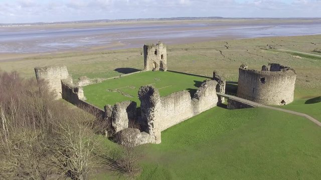 Aerial footage flying over Flint Castle toward the Dee Estuary on a bright spring day.
