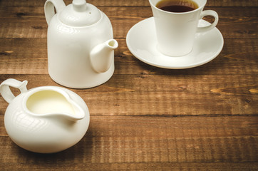 coffee in a white cup, a creamer and a teapot/white teapot, creamer and cup of coffee