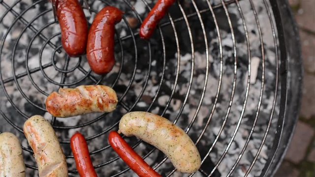 Fresh sausage and hot dogs grilling outdoors on a gas barbecue grill. Beautiful food background