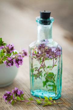 Vintage bottle of thyme infusion and mortar full of thymus serpyllum flowers. Herbal medicine.