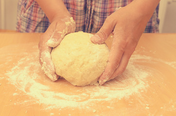 A woman kneads a homemade dough for pizza production.