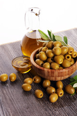 Bottle virgin olive oil and oil in a bowl with some olives