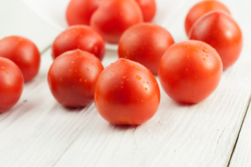Many fresh red and ripe tomatoes scattered on old white wooden planks