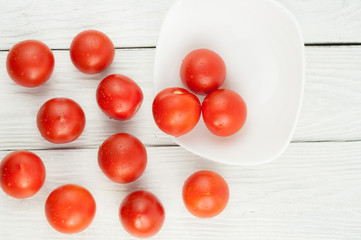 Many fresh red and ripe tomatoes scattered on old white wooden planks