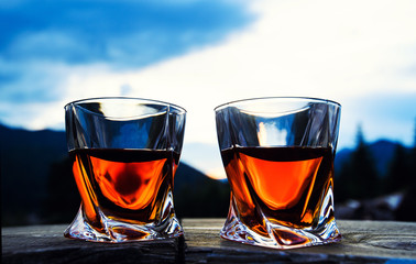 shot of whiskey at sunset dramatic sky on mountain landscape background