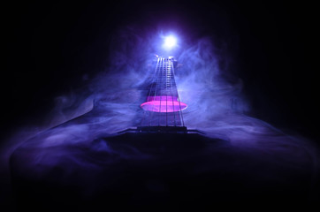 Music concept. Acoustic guitar isolated on a dark background under beam of light with smoke with...