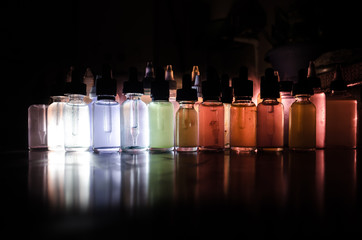 Vape concept. Smoke clouds and vape liquid bottles on dark background. Light effects. Useful as...