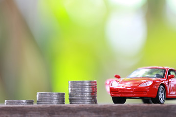 Silver coin of pile with red car model in concept savings to buy a new car.