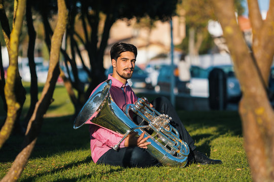 Musician with the tuba sitting on the grass in the Park.