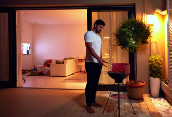 young adult man preparing food for family on evening patio at home