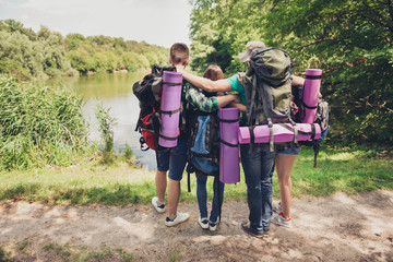 Trekking, camping, harmony, peace concept. Rear view of two couples of friends bonding on the bench of the lake, looking at the beautiful view, enjoy and relax