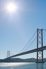 Fototapeta na wymiar Lisbon 25 april suspension bridge againt blue sky and sun