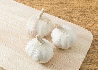 Three Garlic Bulbs on Wooden Cutting Board