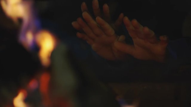 Children Warming Their Hands At A Fireplace Outdoors At Night In Slow Motion. Close Up Shot.