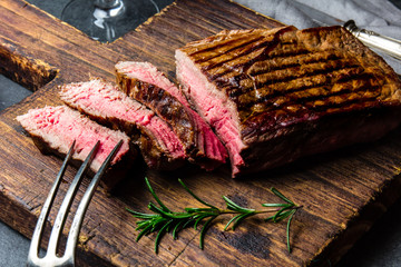 Gesneden gegrilde medium zeldzame biefstuk geserveerd op een houten bord Barbecue, bbq vlees ossenhaas. Bovenaanzicht, leisteen achtergrond