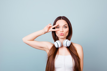 Funky mood! Young attractive brunette model is fooling around with pouted lips, two fingers sign,...