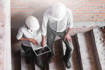 engineer working on checking progress of construction with and laptop at construction site 
