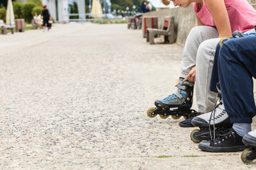 People friends putting on roller skates outdoor.