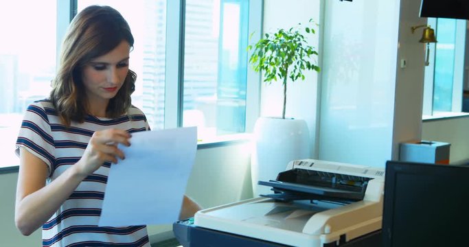 Female executive using photocopier machine in office