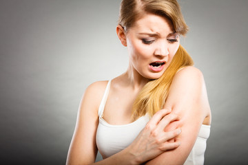 woman scratching her itchy arm with allergy rash