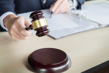 Male Judge In A Courtroom Striking The Gavel on sounding block