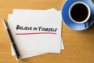 Believe in yourself - handwriting on papers with cup of coffee and pen,motivation concept