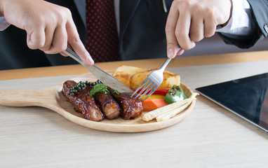 Businessman holding fork and knife eating steak, business and food/restaurant concept