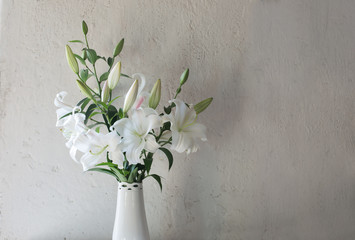 beautiful white lily in vase on background old wall