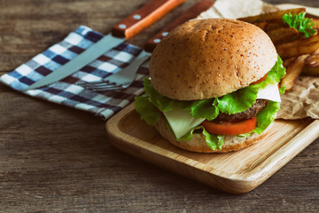 Homemade hamburger on plaid napkin with french fries. Delicious sandwich hamburger with meat or pork ham cheese and fresh vegetable. Hamburger or sandwich is the popular fast food for brunch or lunch.