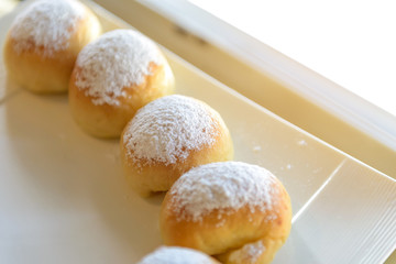 Homemade fresh breads with powdered sugar on top in white plate