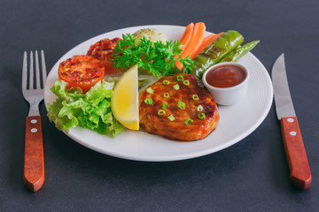 Barbecue pork steak on white plate served with barbecue sauce and vegetables. Pork steak for lunch or dinner on granite table. Moist and soft homemade pork barbecue with mash potato and vegetable.