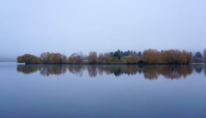 Fototapeta premium Reflection on the water of the forest landscape during twilight time