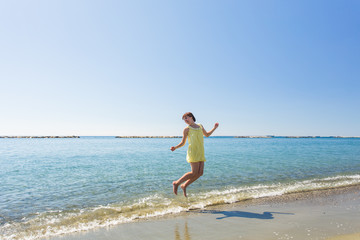 Fototapeta na wymiar happy young woman jumping on the beach of sea