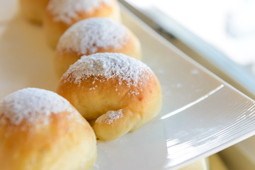 Homemade fresh breads with powdered sugar on top in white plate