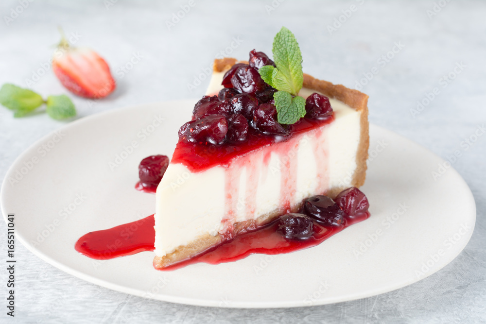 Wall mural Slice of new york cheesecake with cherry sauce and mint leaf on top.