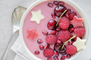 red pink smoothie bowl with cherry, strawberry, raspberries and pomegranate