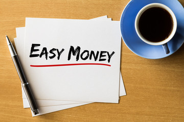 Easy money - handwriting on papers with cup of coffee and pen, finance concept