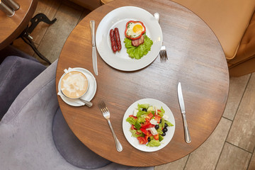 Fried eggs with sausage and salad on table. Top view