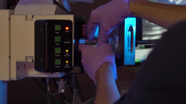 Scientist in a laboratory put samples into electron microscope for investigation