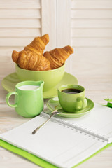 Coffee with milk and croissants and a notepad.