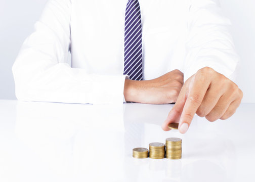 Close up of business man hand holding coins and putting on coin stack for financial ideas concept