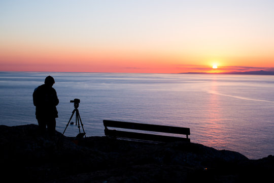 man photographer taking photos of sunset at the sea