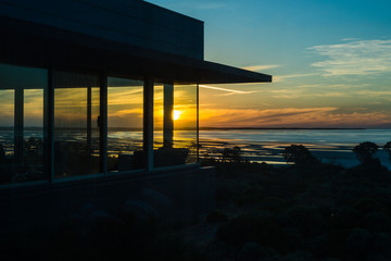 silhouette of modern beach house overlooking an ocean sunset