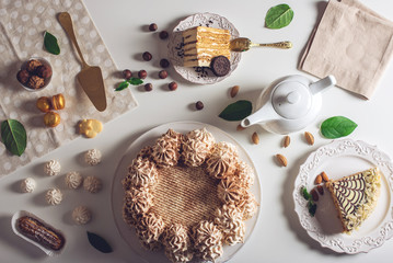 Decorated dessert table where the cake with meringue, layered pieces of cake. Arrangement of delicious sweets, top view